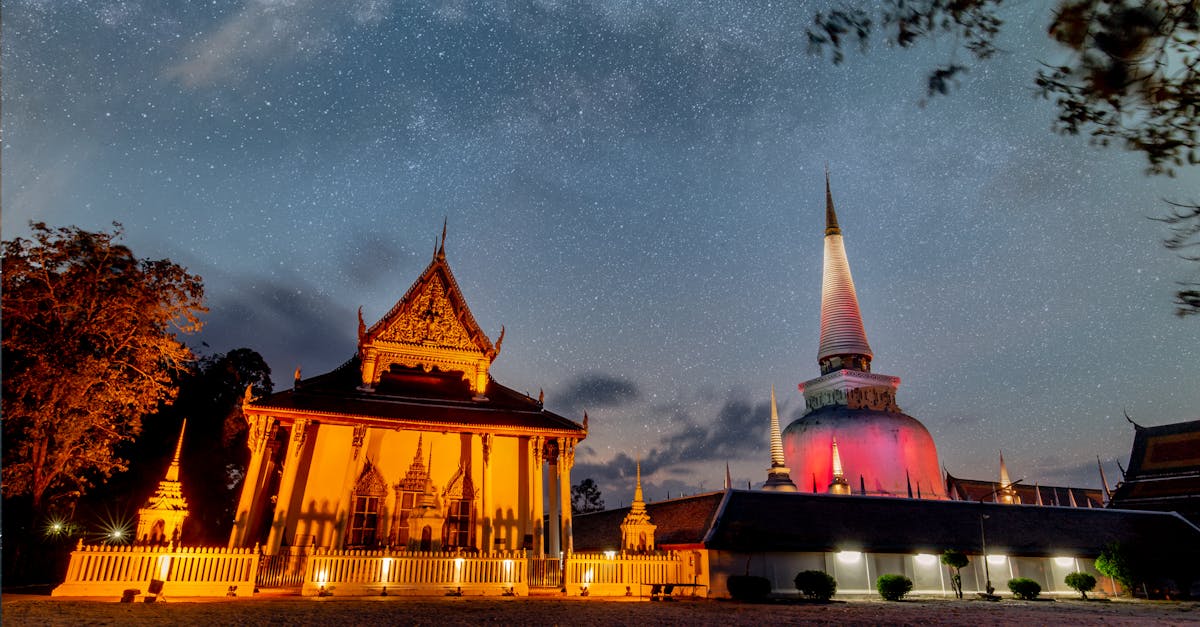 Illuminated Buddhist temple with starry sky in Thailand at night.