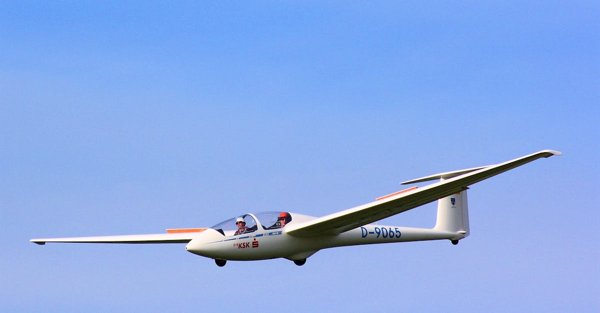 A two-seater glider flying gracefully against a backdrop of clear blue sky.