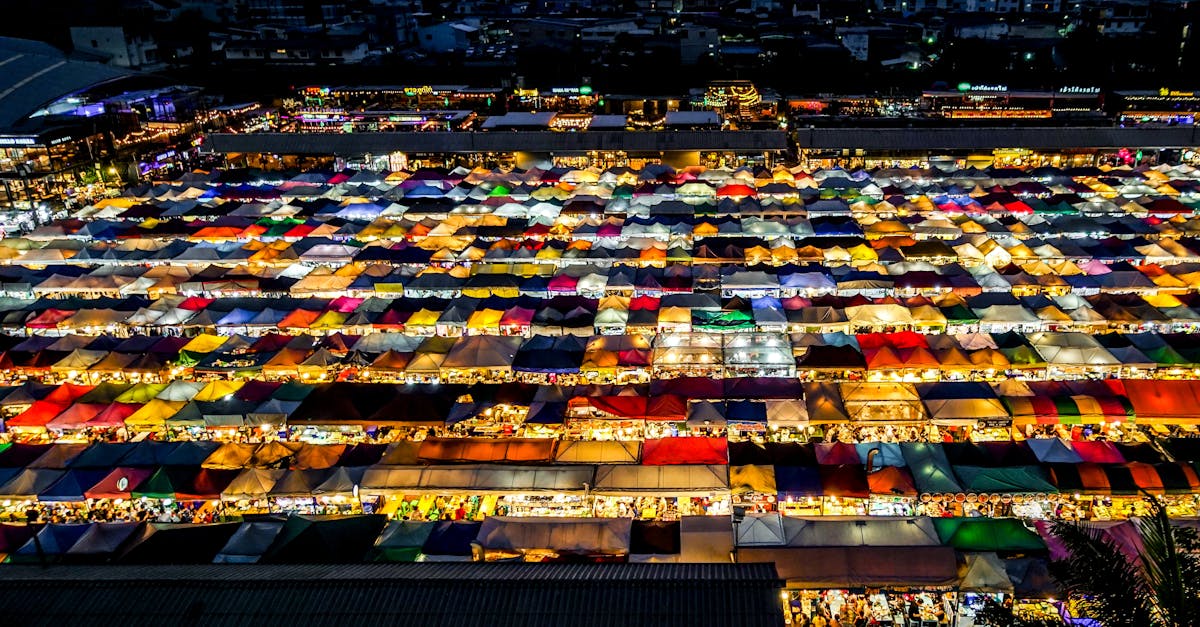 A colorful aerial shot of an illuminated night market in Bangkok, Thailand, showcasing diverse and vibrant stalls.