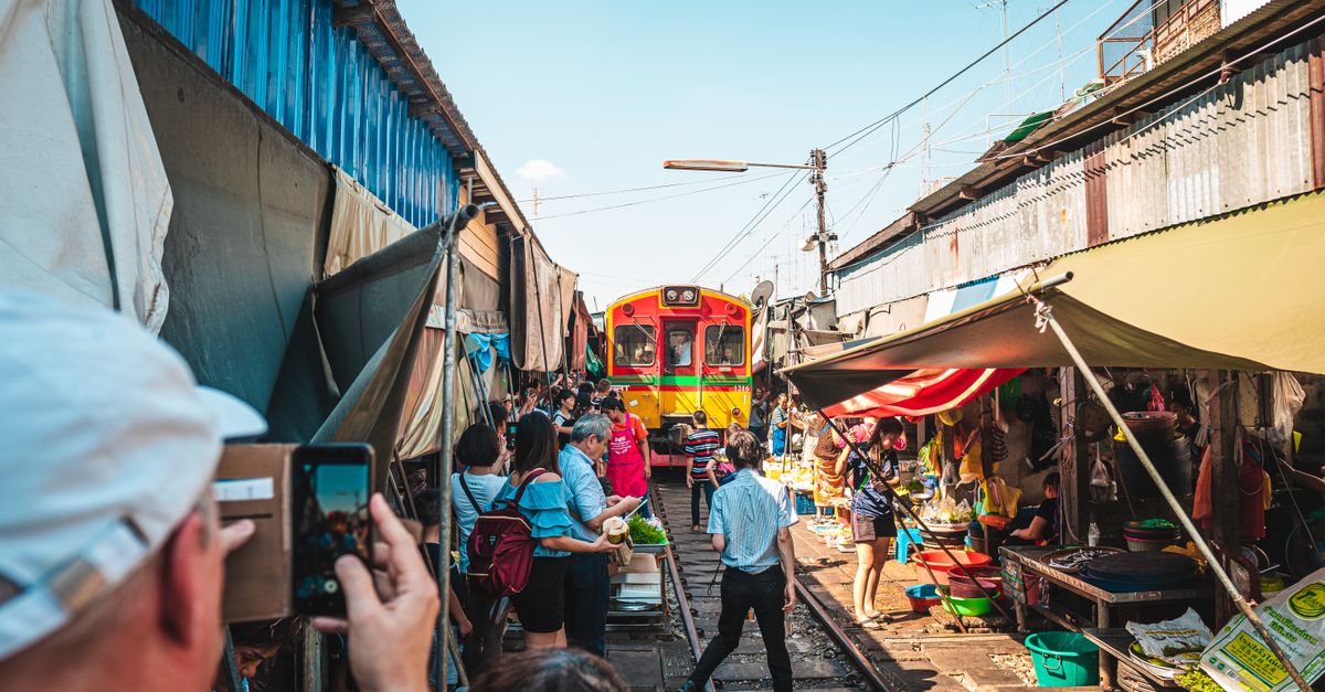 Colorful scene of Mae Klong Railway Market with train passing through in Bangkok, Thailand.
