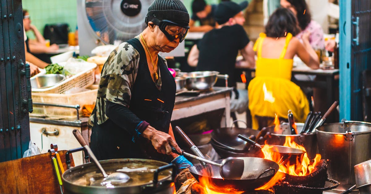 Experienced chef skillfully cooking over open flames in Bangkok's bustling street market.