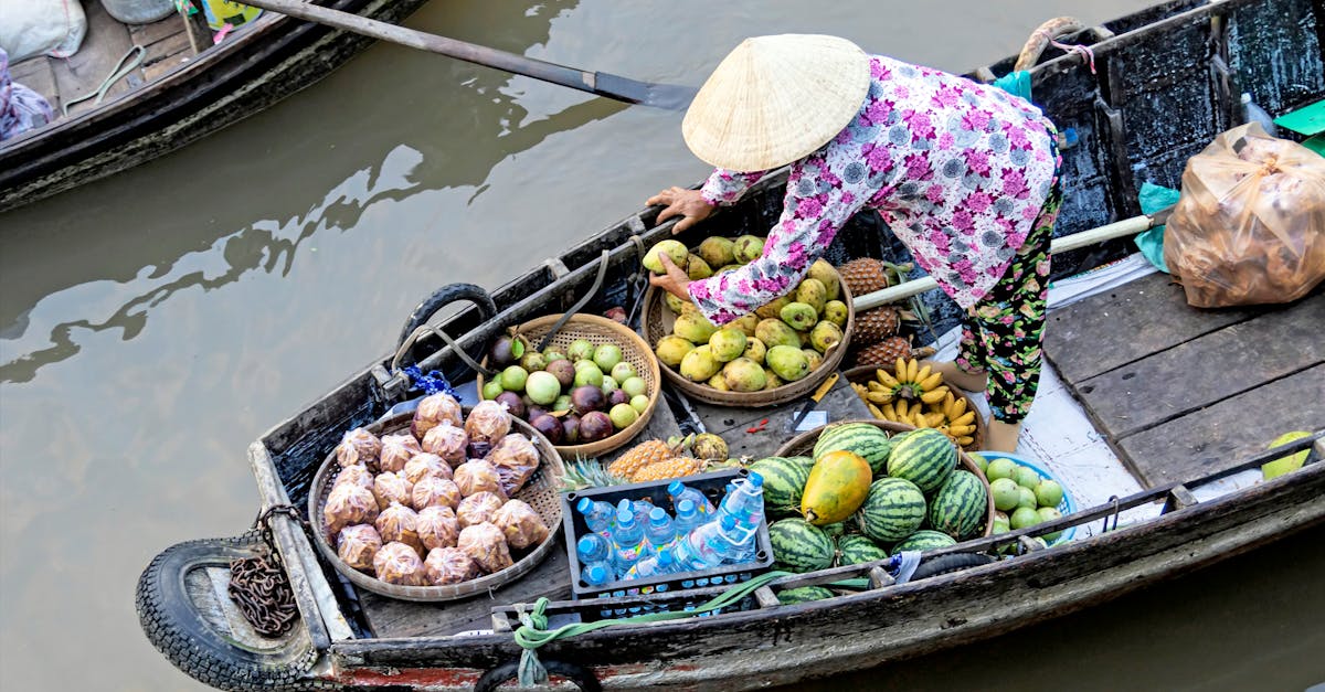 A fruit vendor on a traditional boat at a floating market in Cần Thơ, Vietnam, selling fresh produce.