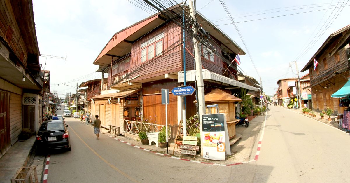 A vibrant day scene of a traditional wooden street in Southeast Asia with local flags and architecture.
