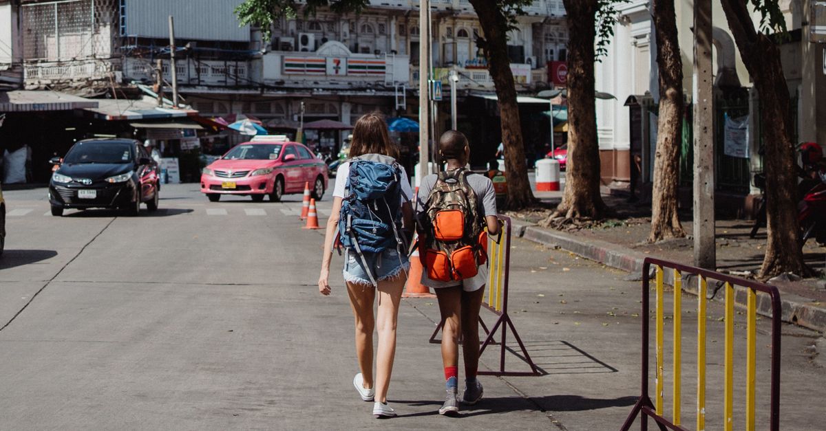 Two backpackers walk down a lively street, embodying urban exploration and travel.