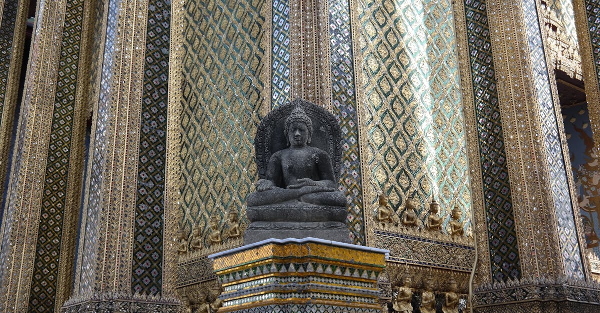 Intricate Buddhist sculpture surrounded by detailed golden patterns in a Thai temple.