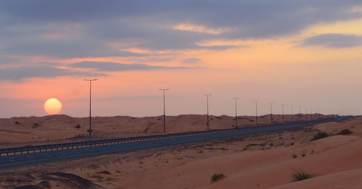 Captivating view of a desert highway at sunset with soft pastel skies and endless road.