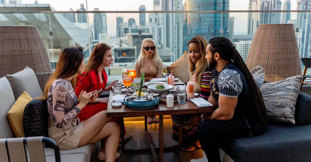 Group of friends dining on a rooftop terrace with a stunning view of Dubai skyline.