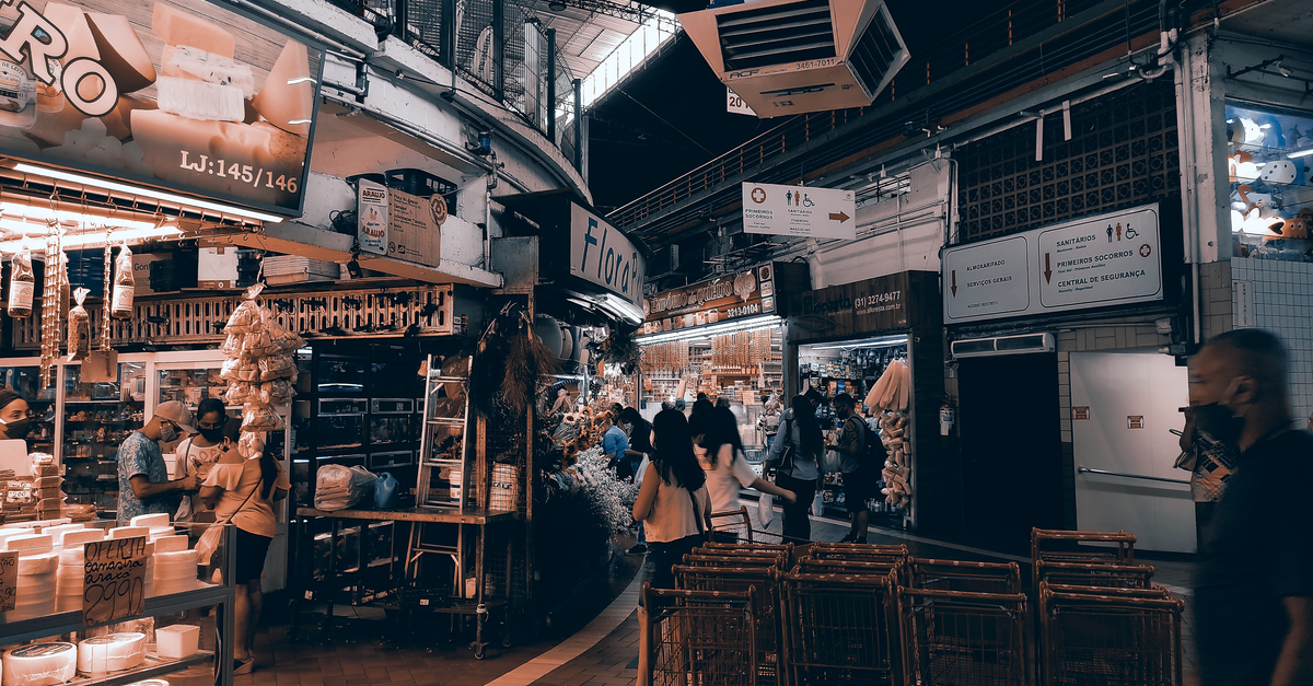 Vibrant indoor market filled with shoppers, food stalls, and lighting. Captures urban market vibe.