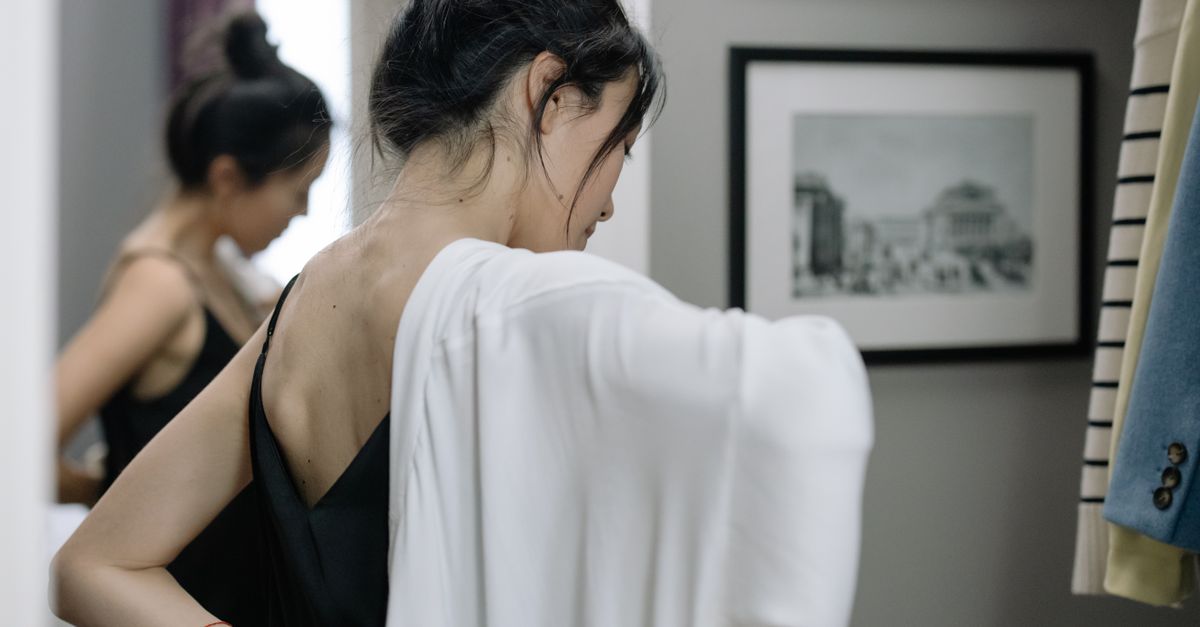 A woman tries on clothes in a modern dressing room with artistic decor.