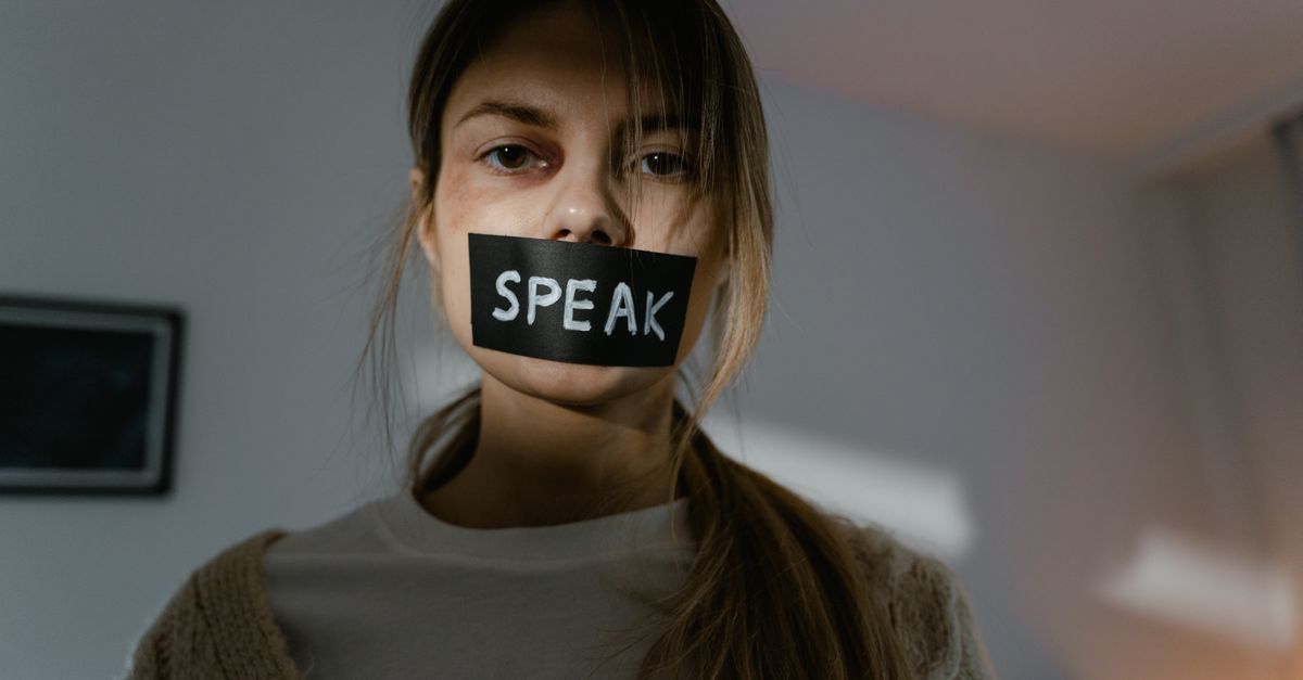 Woman with 'speak' tape over mouth.