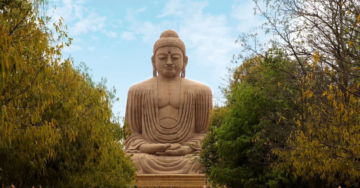 An awe-inspiring view of the Great Buddha Statue in Bodh Gaya, surrounded by lush greenery.