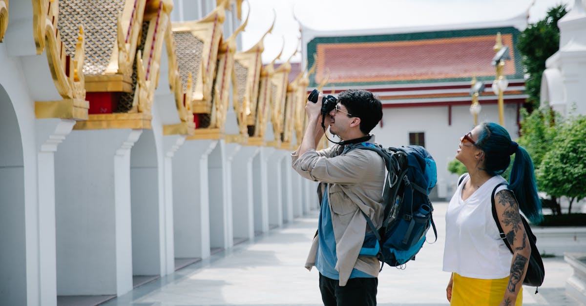 A couple with backpacks photographing a temple during daylight visit.