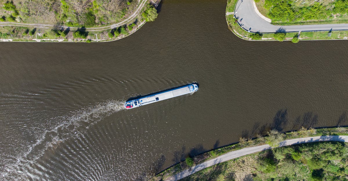 Aerial view of a ship sailing through a scenic canal surrounded by greenery, showcasing tranquil waterway travel.