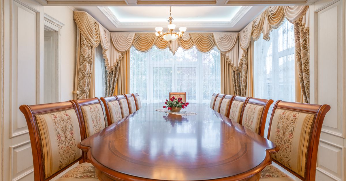 A beautifully decorated dining room featuring a long wooden table and ornate curtains, exuding elegance and luxury.
