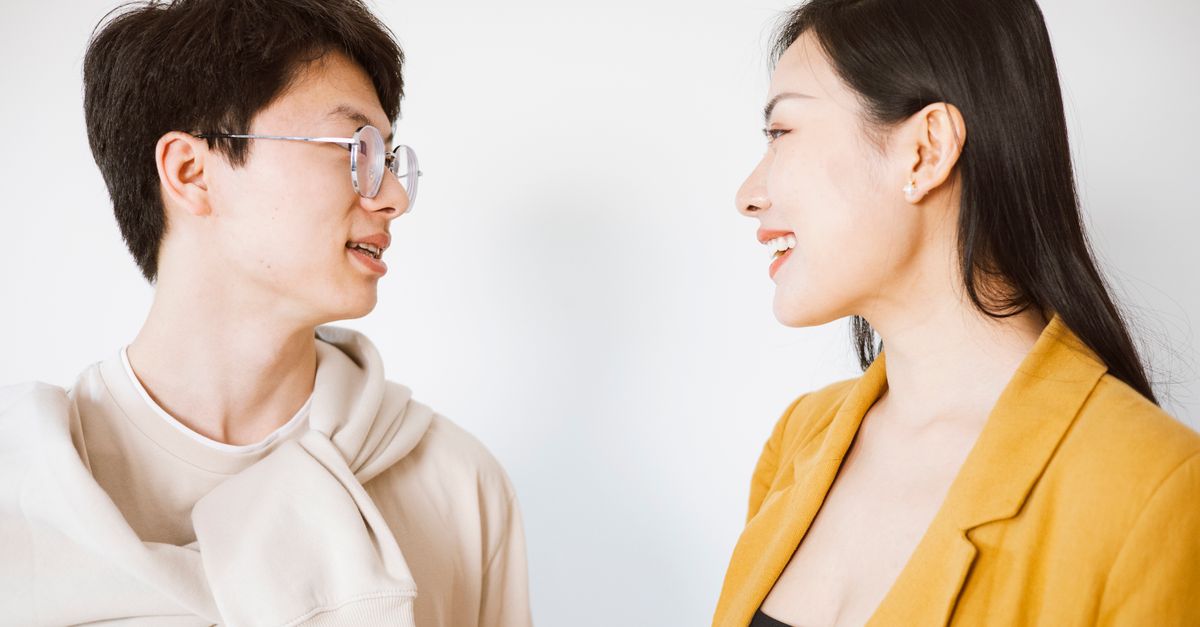 Smiling man and woman having a friendly conversation in a bright indoor setting.