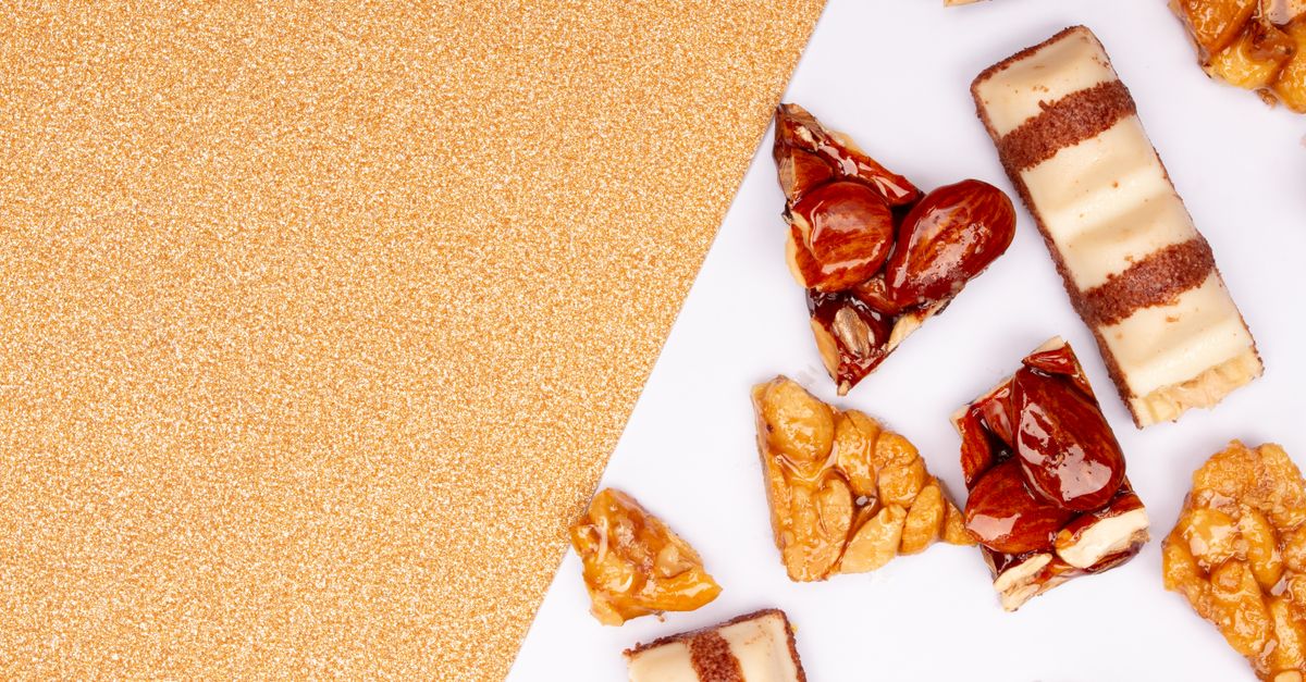 Close-up of assorted candied nuts and sweets on a white and gold background, perfect for food photography.