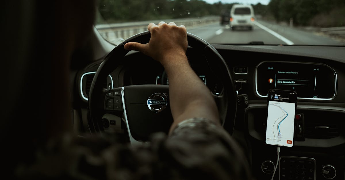 A driver navigates the highway with a smartphone GPS, showcasing modern car interior design.