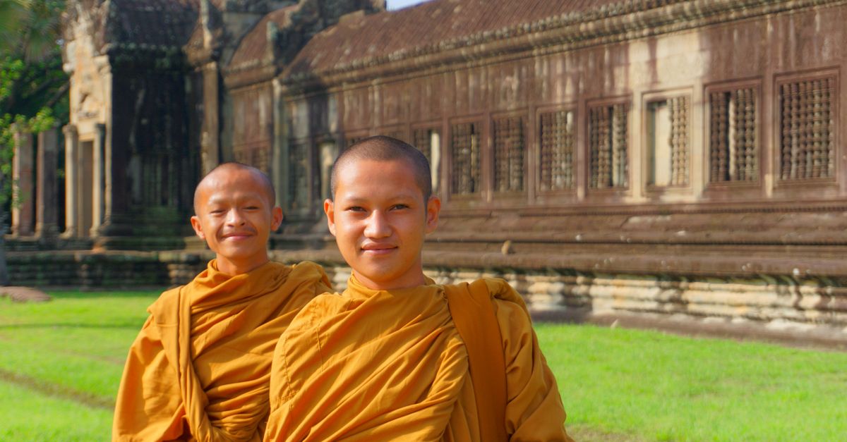 Two young monks in saffron robes at Angkor Wat, Cambodia during a sunny day.